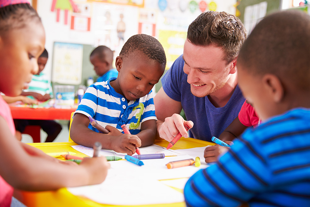 Volunteer helping child draw